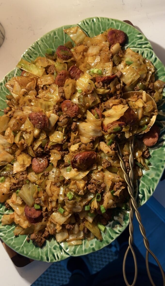 dirty cabbage recipe on green platter with gold utensils