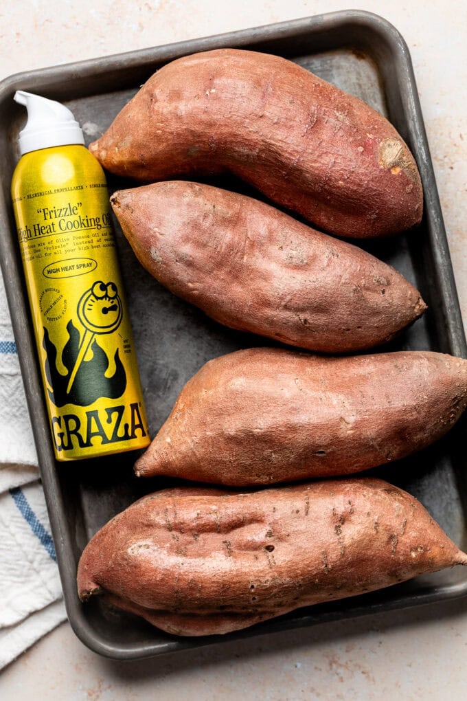 sweet potatoes with nonstick spray can on baking sheet