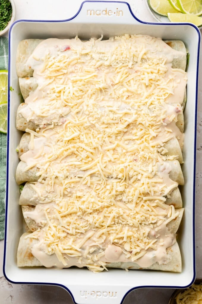 shredded cheese on top of enchiladas in baking pan