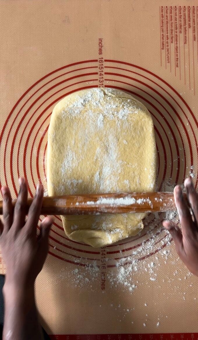 black hands rolling out dough on pastry mat