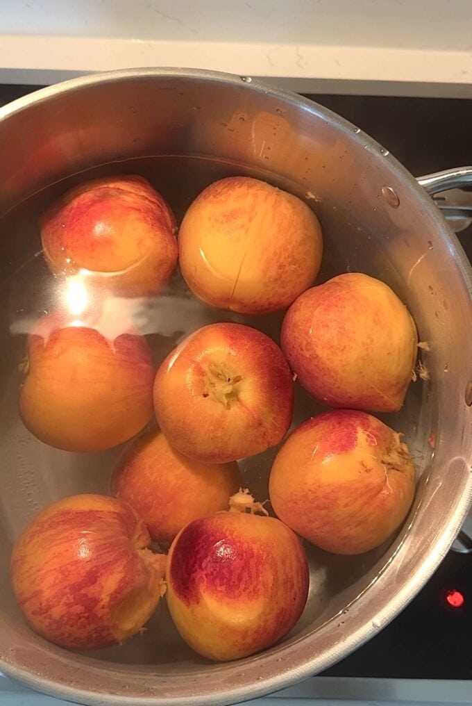 fresh peaches boiling in pot of water