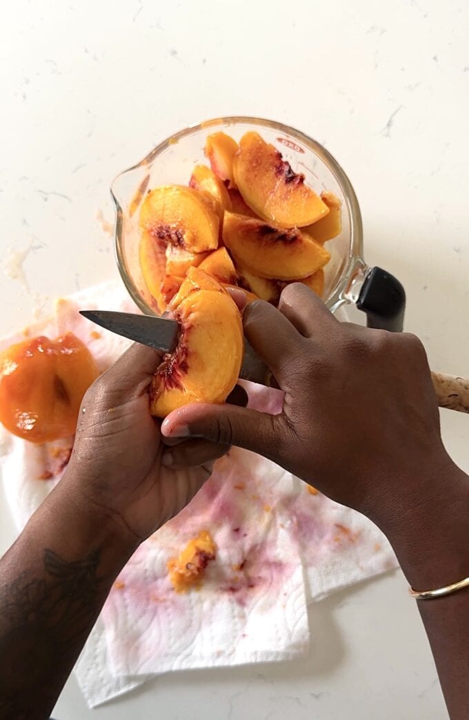 black hand slicing peaches